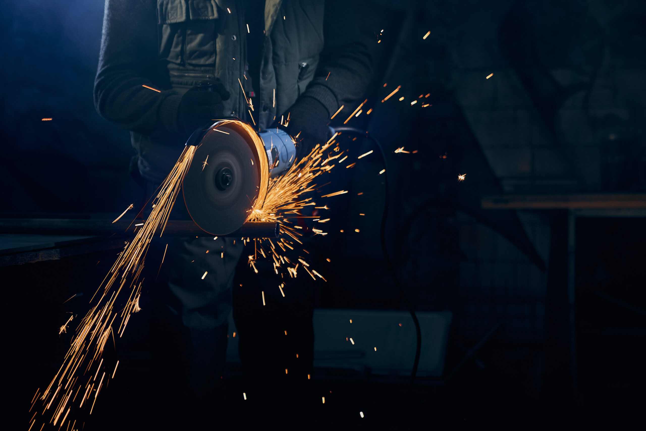 Young man cutting with rotating disc for metal with sparks. Com o acumulado de janeiro a maio, as importações totais de aço já somam 2,93 milhões de toneladas em 2025 — uma alta anual de 26,8%