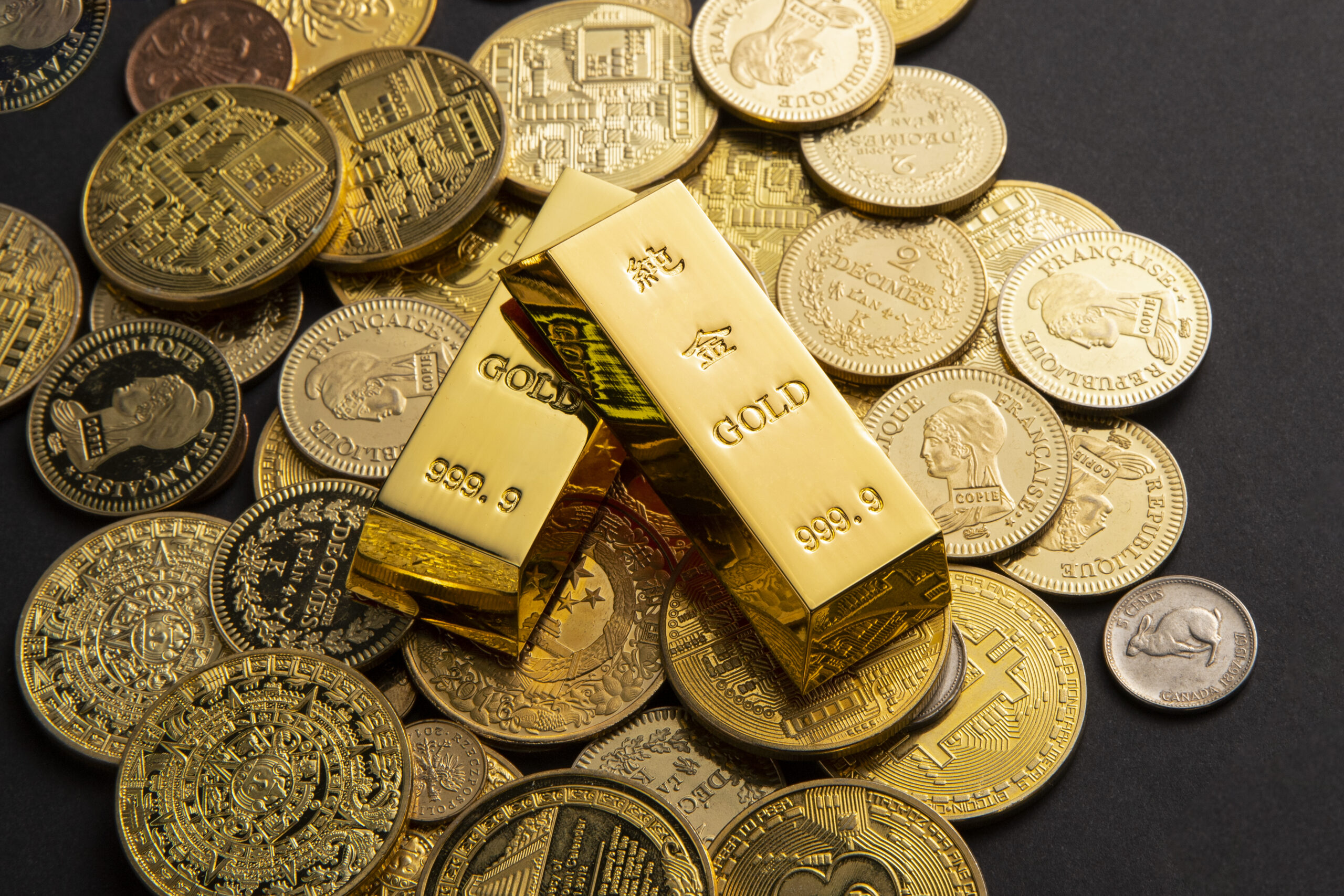 Coins, and gold bars scattered on a table As exportações de ouro de Minas Gerais atingiram US$ 297,7 milhões em outubro, com crescimento de 46,6%. O aumento é impulsionado pela alta cotação do metal e pela instabilidade econômica global