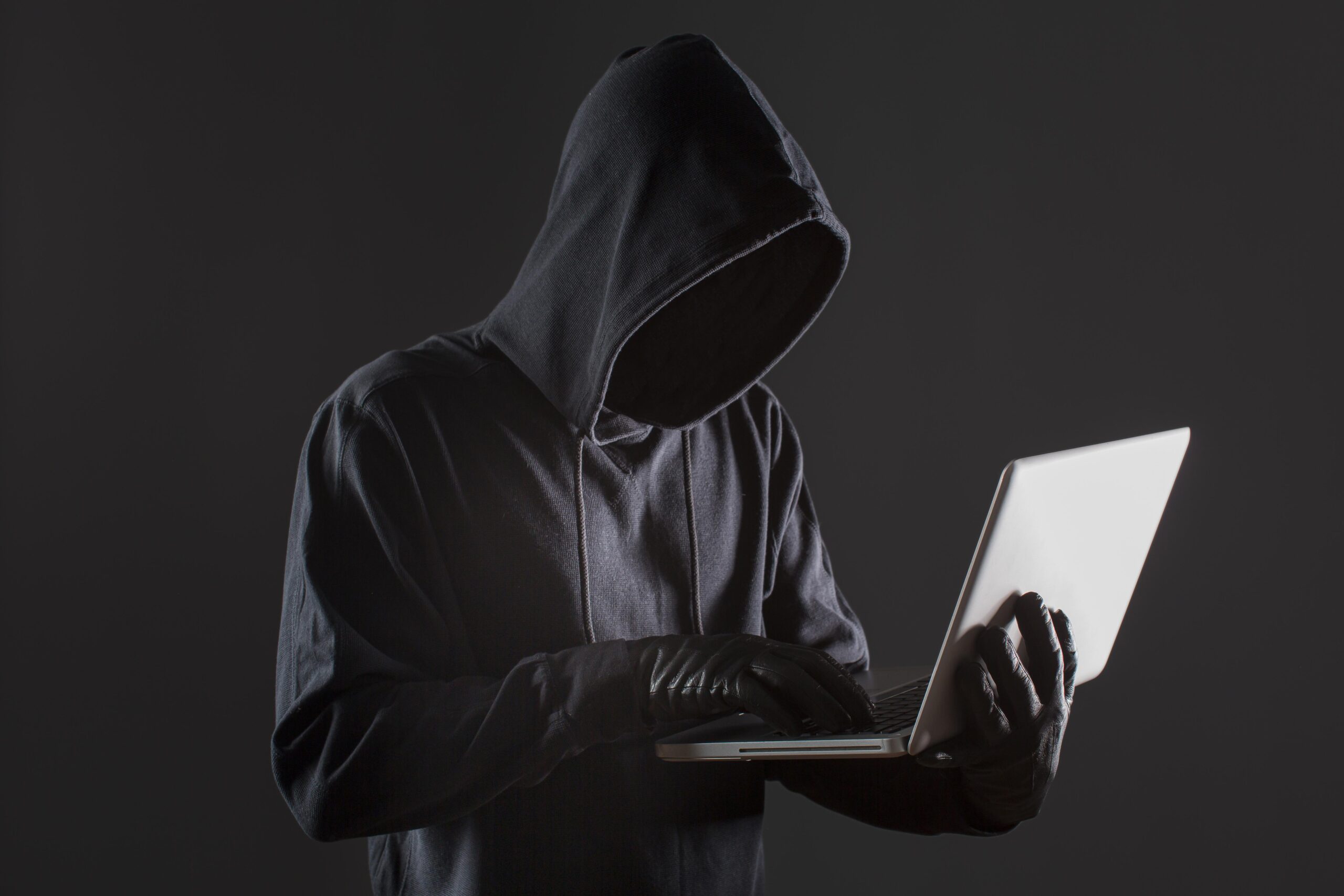 vista-lateral-hacker-masculino-com-luvas-e-laptop CSN alerta para golpe que utiliza seu nome para enganar candidatos a empregos em Volta Redonda. Saiba como identificar e se proteger dessa fraude